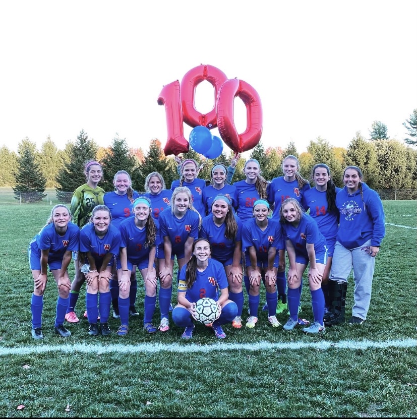Lady Warriors posing for a picture with a 100 goal balloon
