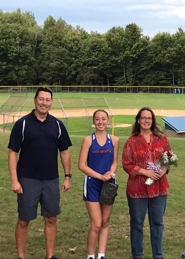 Erika poses with her parents at Cross Country Senior Night 2022.