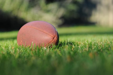 Photo of a football laying in the grass on a field.