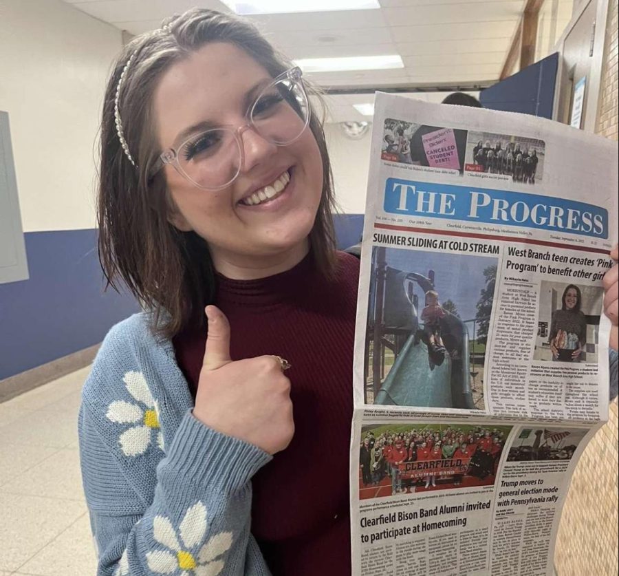 Raven Myers holding The Progress newspaper that features her article.