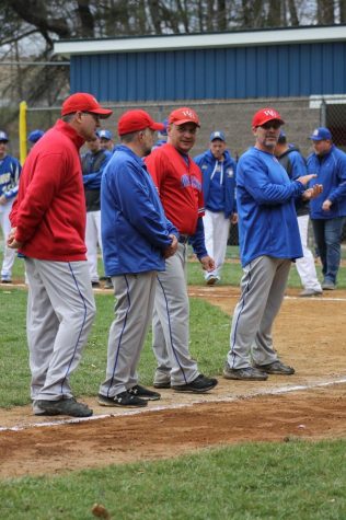 The West Branch baseball coaches stand along the third base line as players are announced.