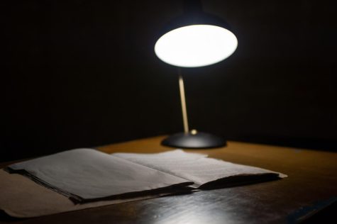 A desk lamp highlights a folder of detective cases; a known symbol of mystery.