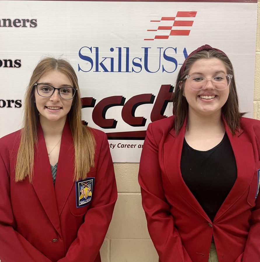 Raven Myers and Alaina Royer stand in front of the CCCTC SkillsUSA board.