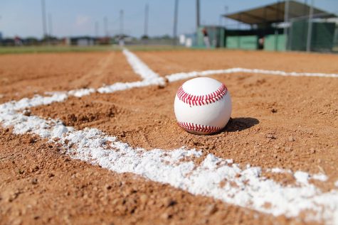 A photo of a baseball left on the field unnoticed after practice.