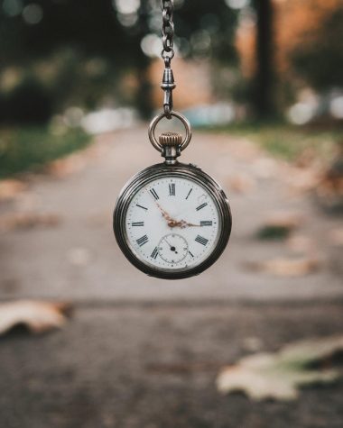 A small pocket watch against a blurry background showing the passing of time.