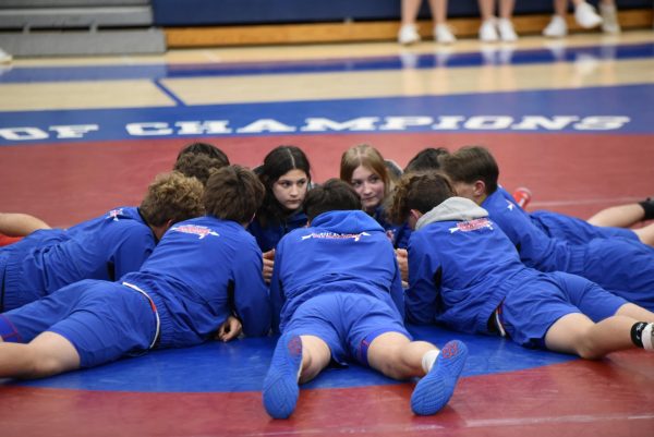 Natalie and Holly discussing strategy in a group huddle with the West Branch wrestling team.