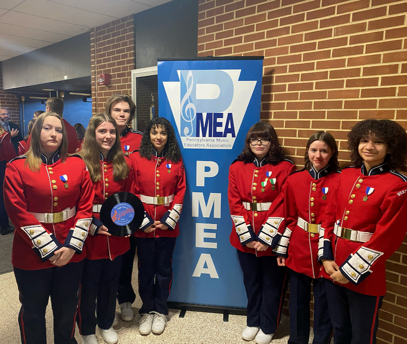 The group of seven Warrior musicans positioned in front of the PMEA sign during the district festival.